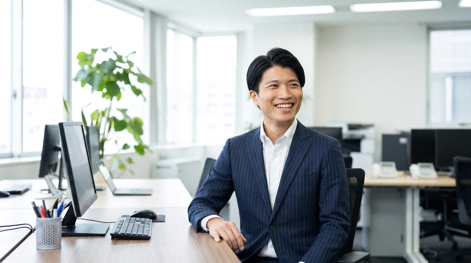 執務席のデスクで、笑顔を見せる板倉さん